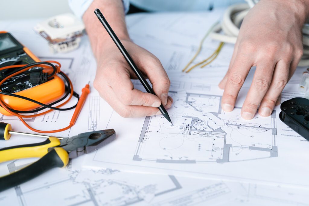 A person draws on blueprints of a building to plan for a structured cabling installation.