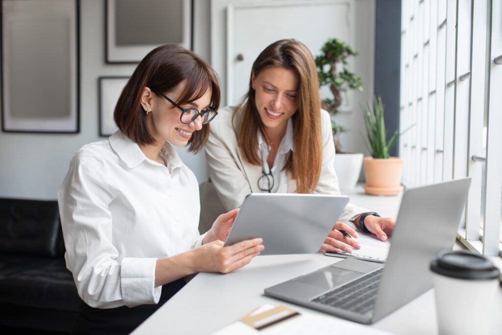 Two businesswomen working on a tablet together.