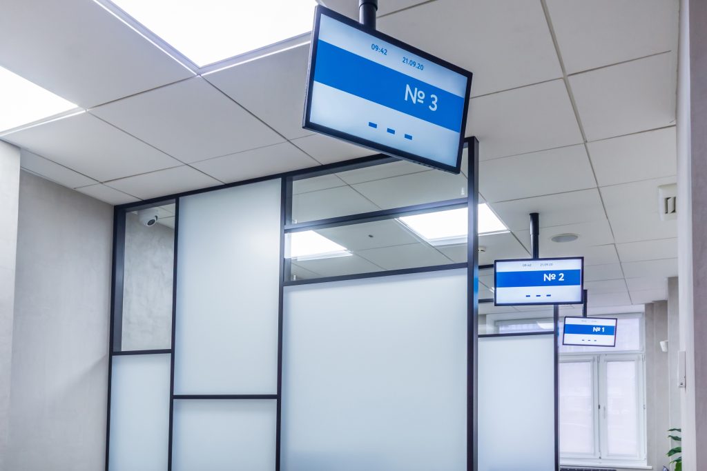 A modern waiting room with a number of small screens hanging from the ceiling
