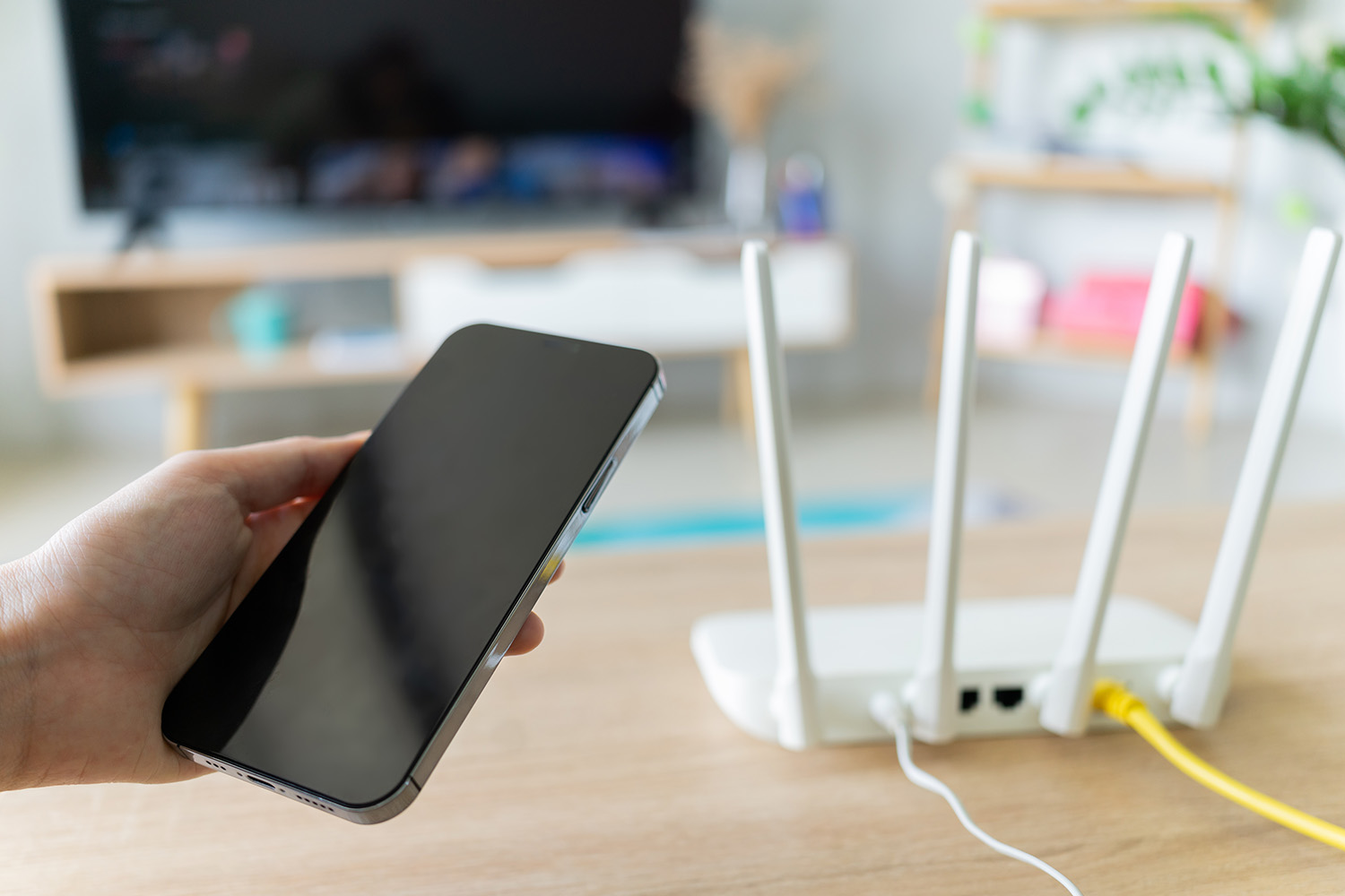 Person holding a smartphone near a Wi-Fi router, possibly setting up or testing a home internet connection.